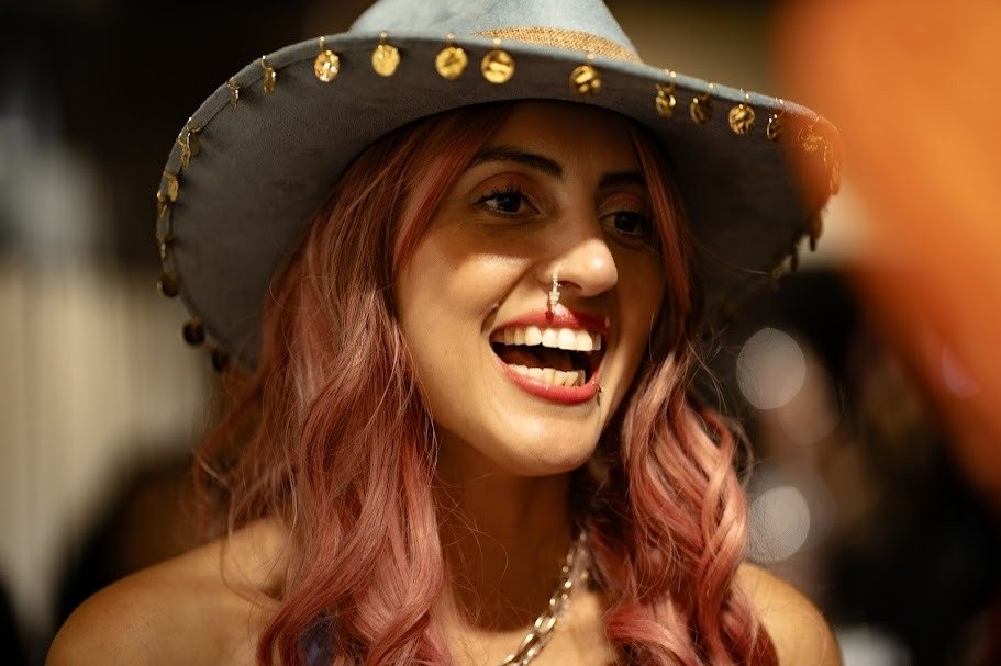 Invitada riendo con un sombrero adornado con tachuelas